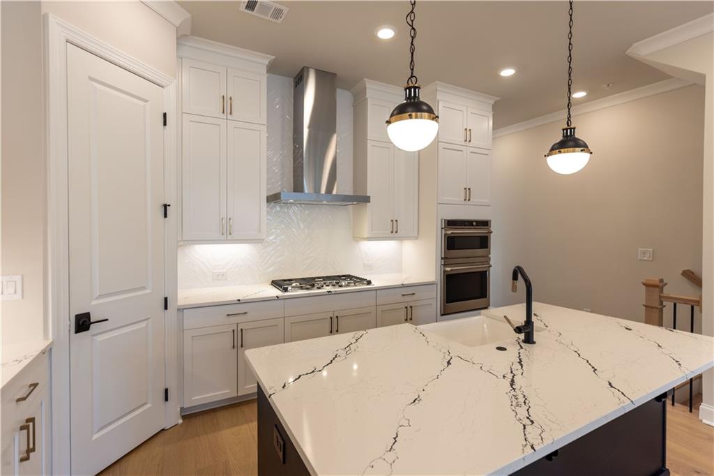 a kitchen with a white center island a sink stainless steel appliances and cabinets