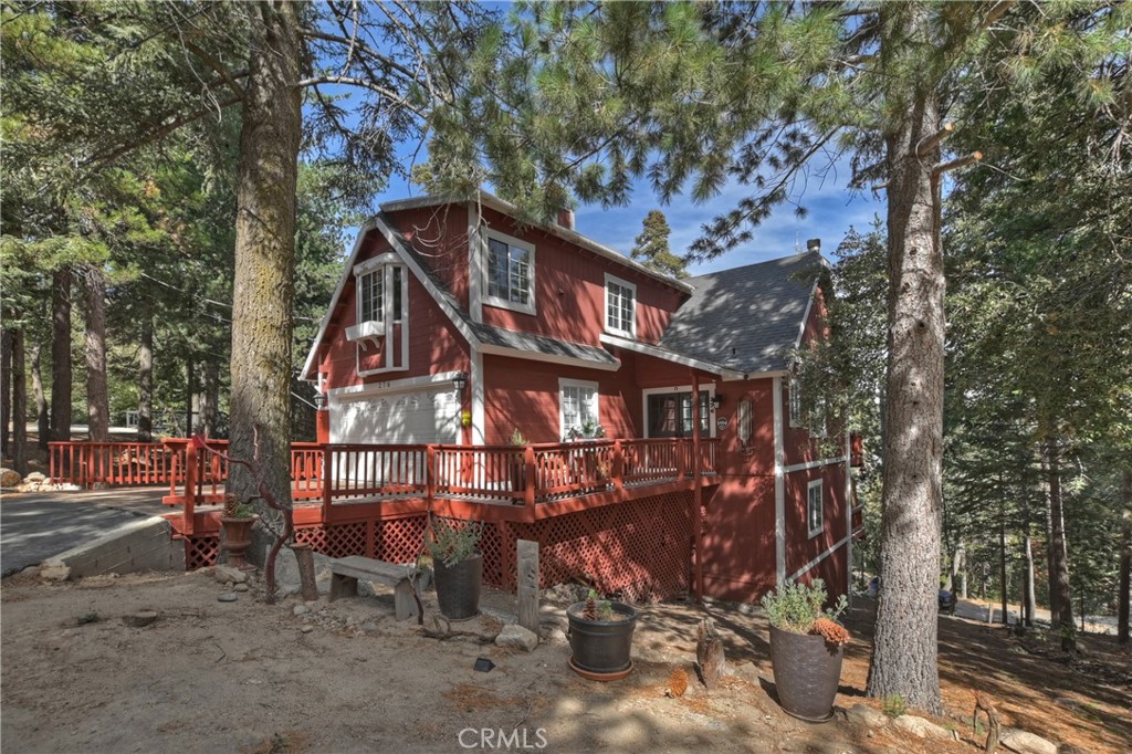 a view of a wooden house with a large tree and wooden fence