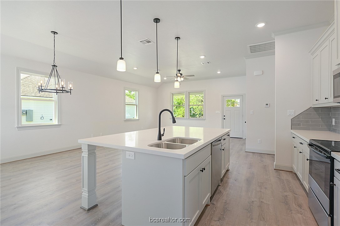 a kitchen with kitchen island a sink stainless steel appliances and a chandelier