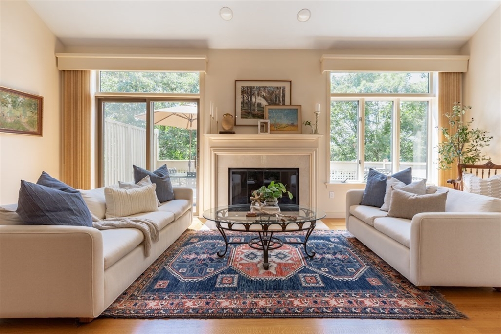 a living room with furniture a rug a large window and a fireplace