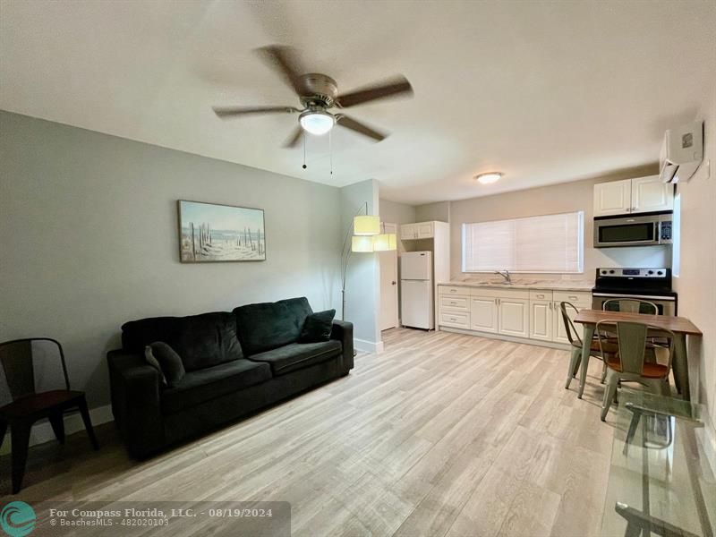 a living room with furniture and a flat screen tv with kitchen view