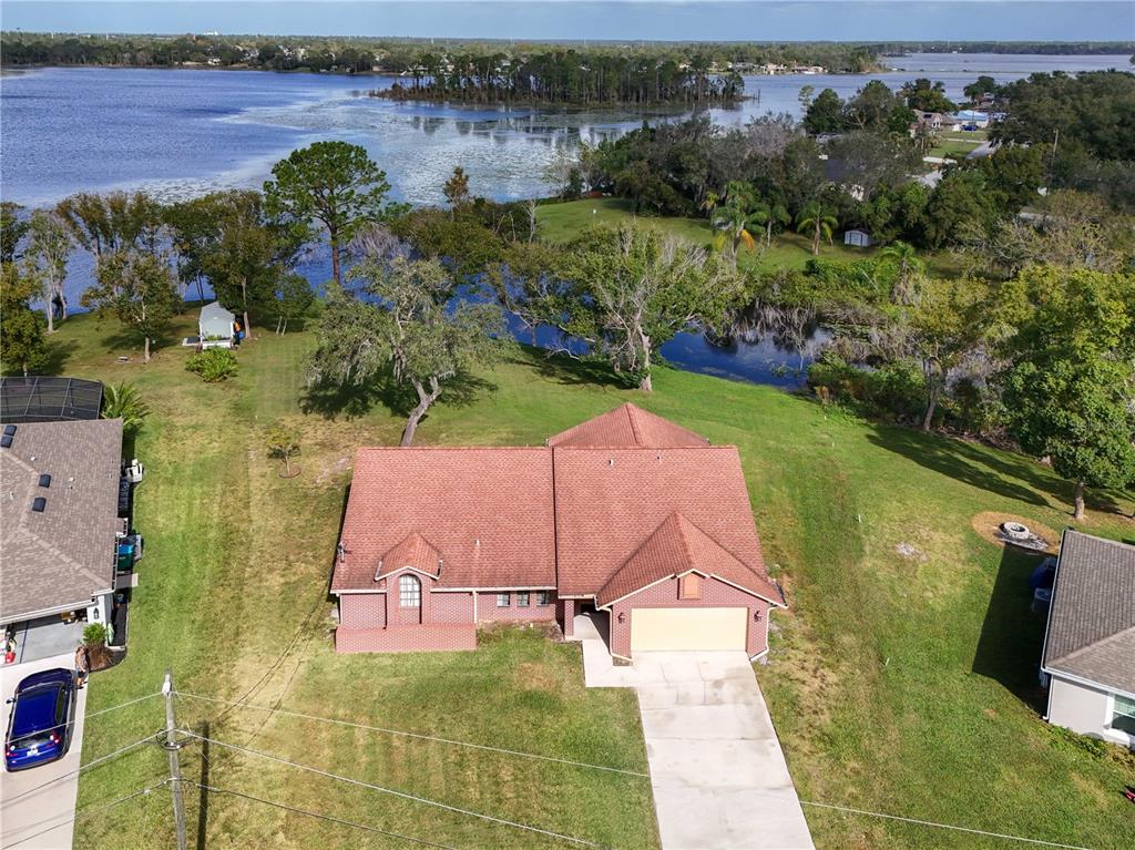 an aerial view of a house with a yard and lake view