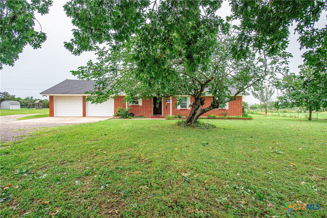 a view of a house with backyard and a tree