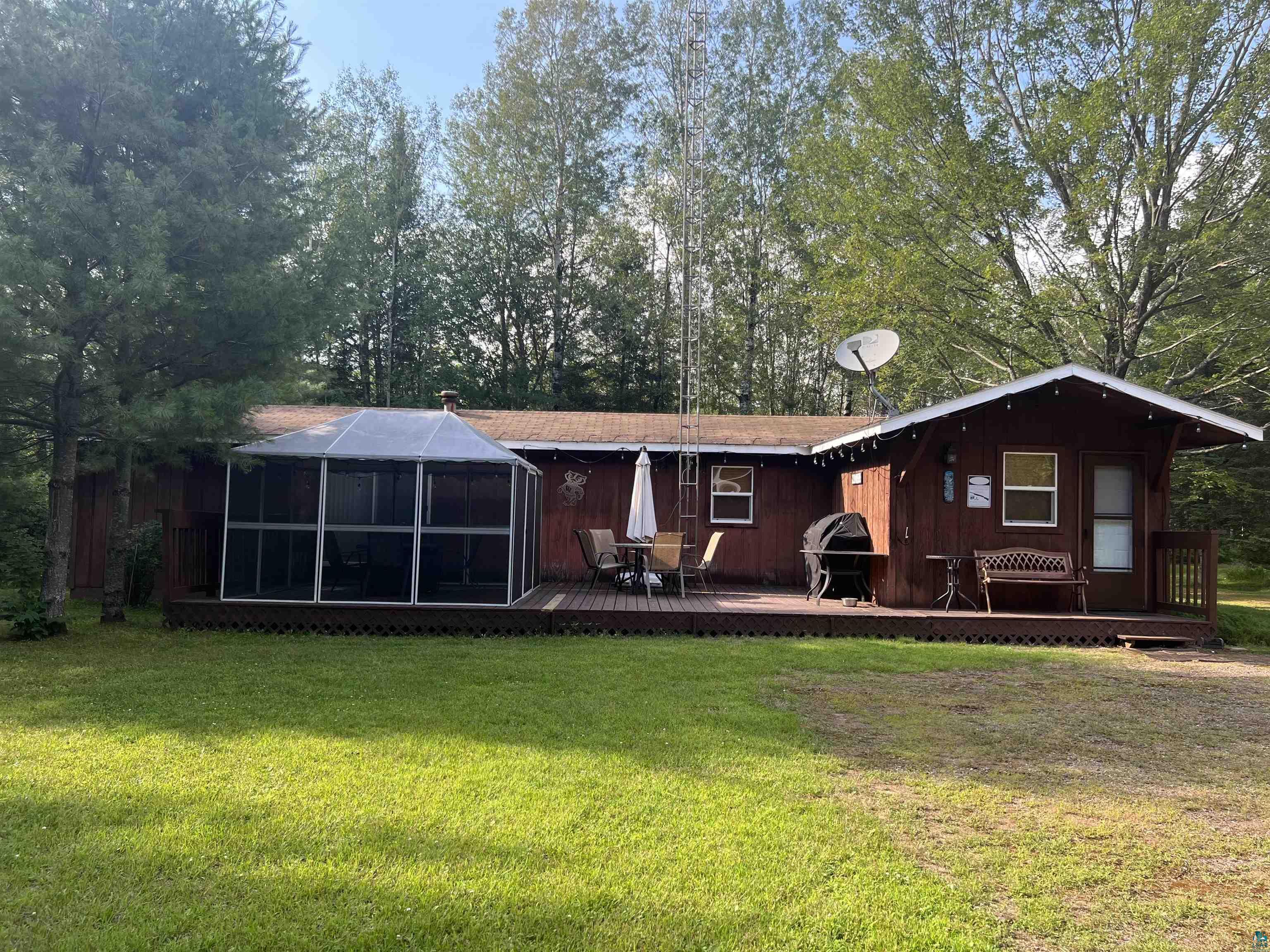 Back of property with a sunroom, a wooden deck, and a lawn