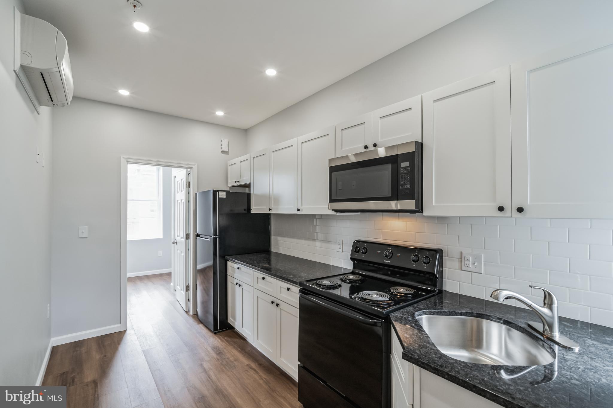 a kitchen with granite countertop a refrigerator stove and sink