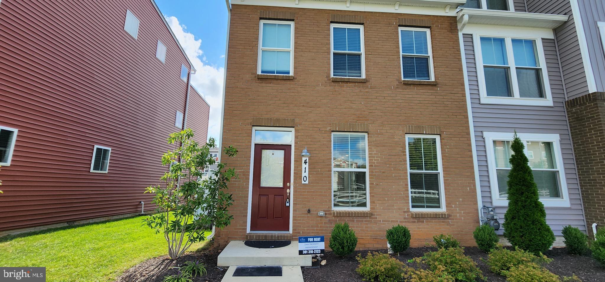 a view of a brick building with a yard and potted plants