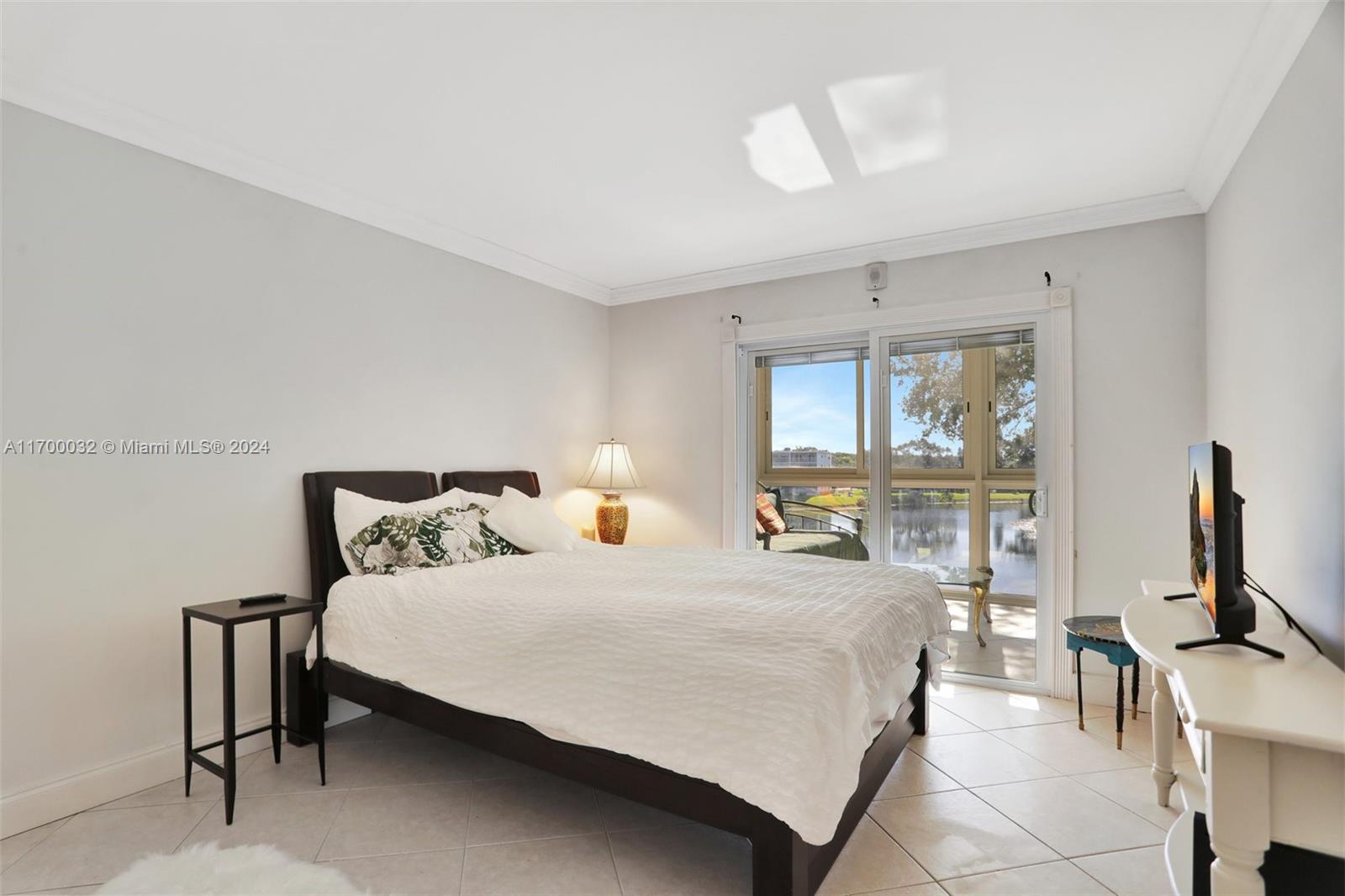 a bedroom with a bed a large window and flat screen tv