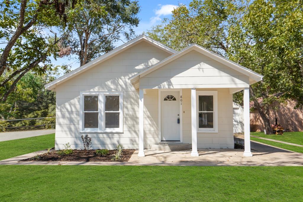 a front view of a house with a yard and trees