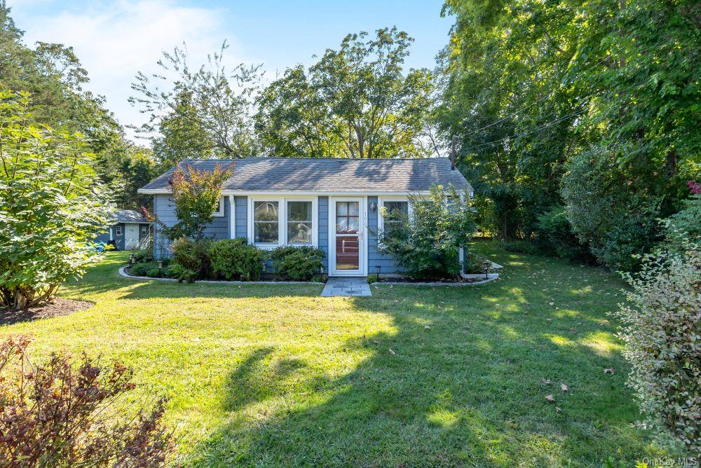 a front view of house with yard and trees in the background