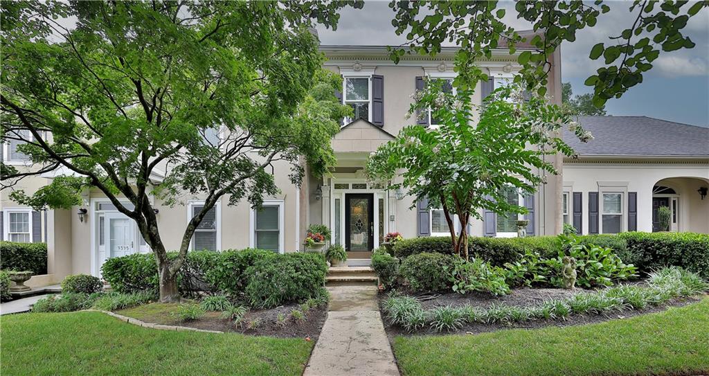 a front view of a house with a yard and potted plants