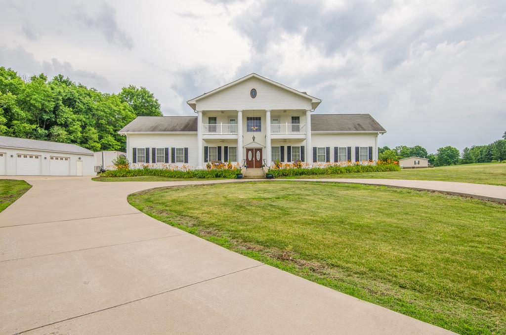 a front view of a house with a garden and lake view