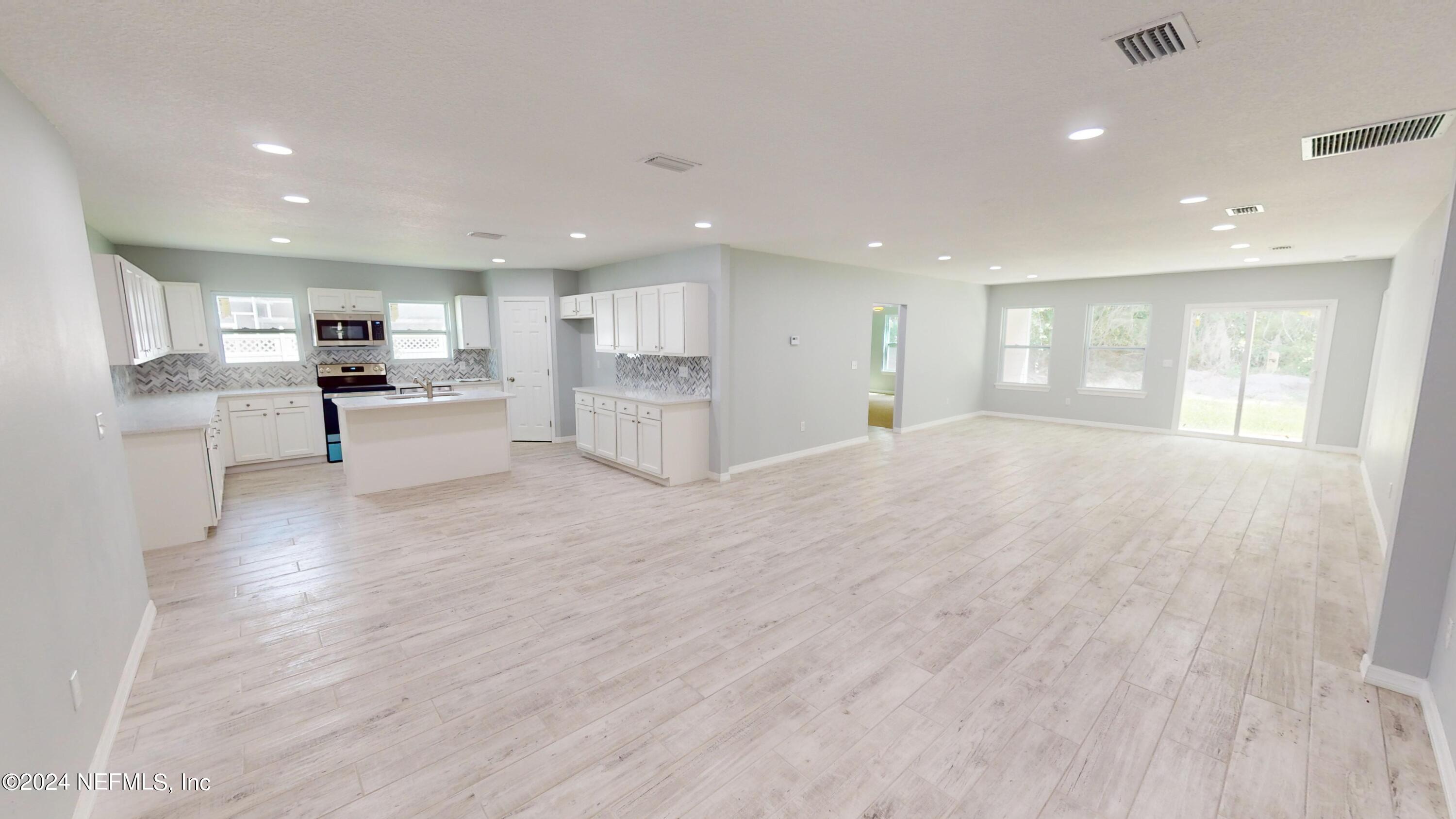 a view of kitchen with kitchen island wooden floors appliances and cabinets