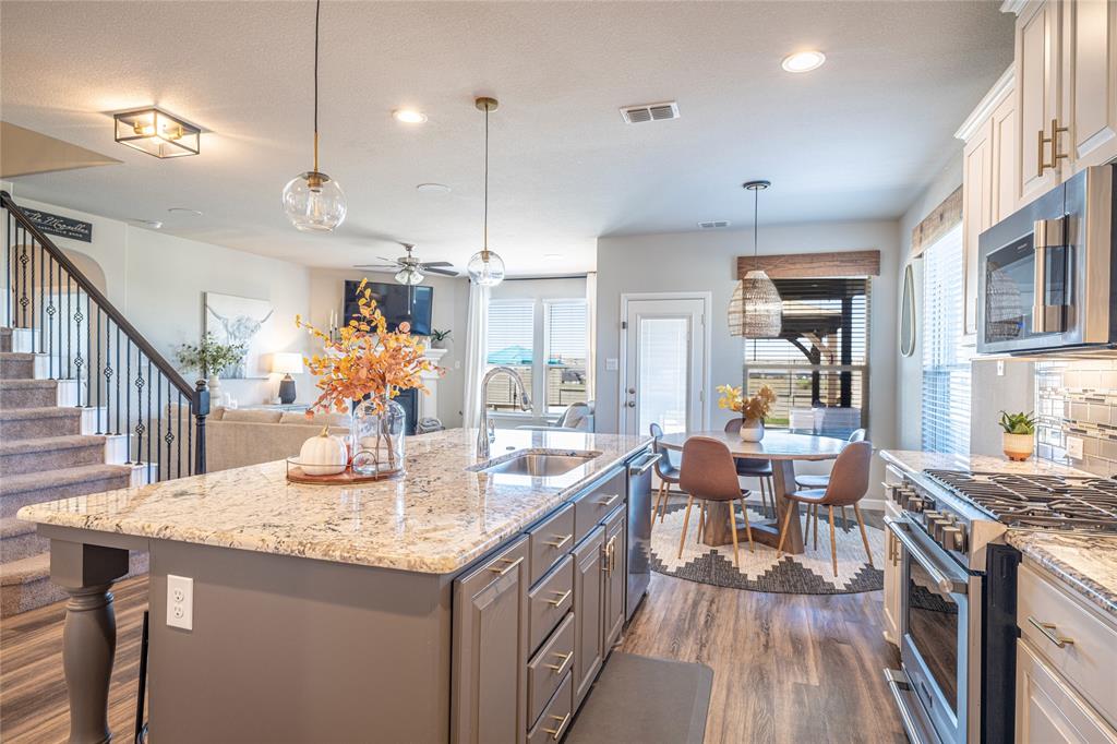 a kitchen with stainless steel appliances granite countertop a kitchen island a stove a sink a dining table and chairs