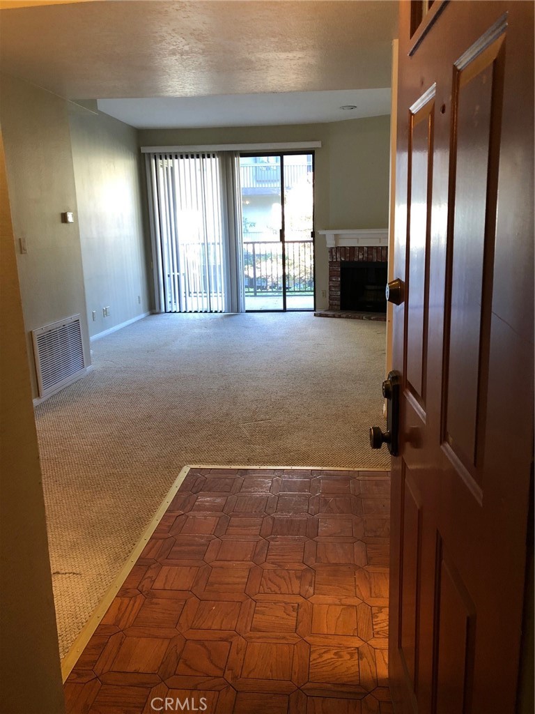 a view of an empty room with a fireplace and a window