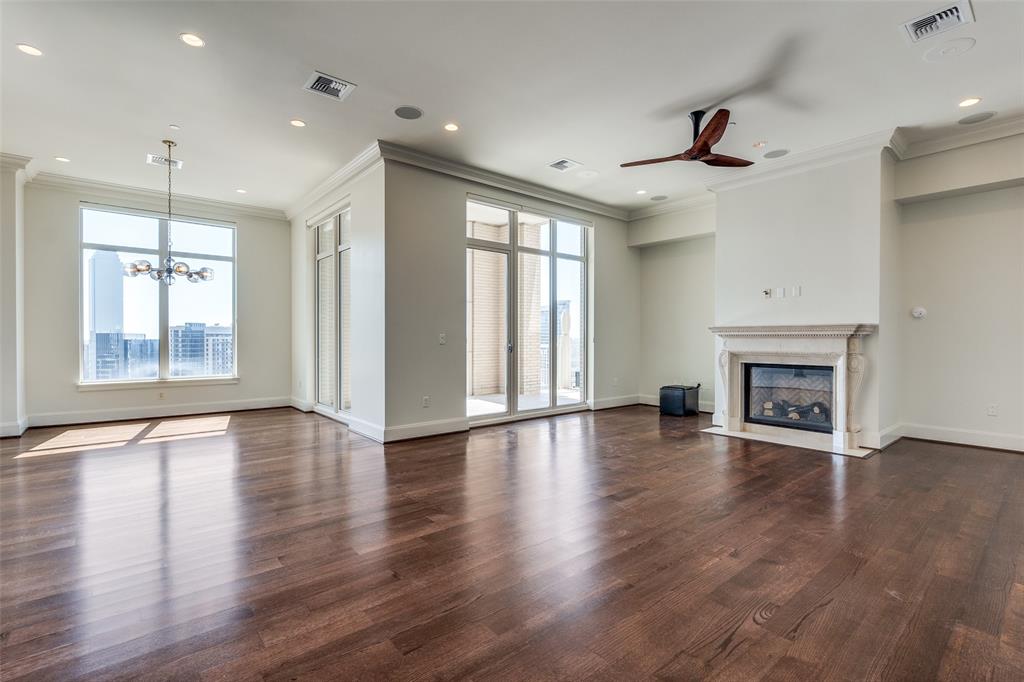 an empty room with wooden floor fireplace and windows