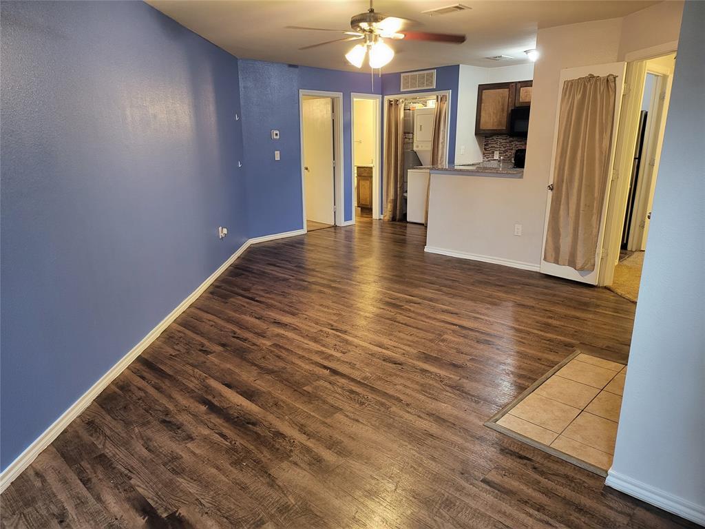 a view of a hallway with wooden floor and a kitchen