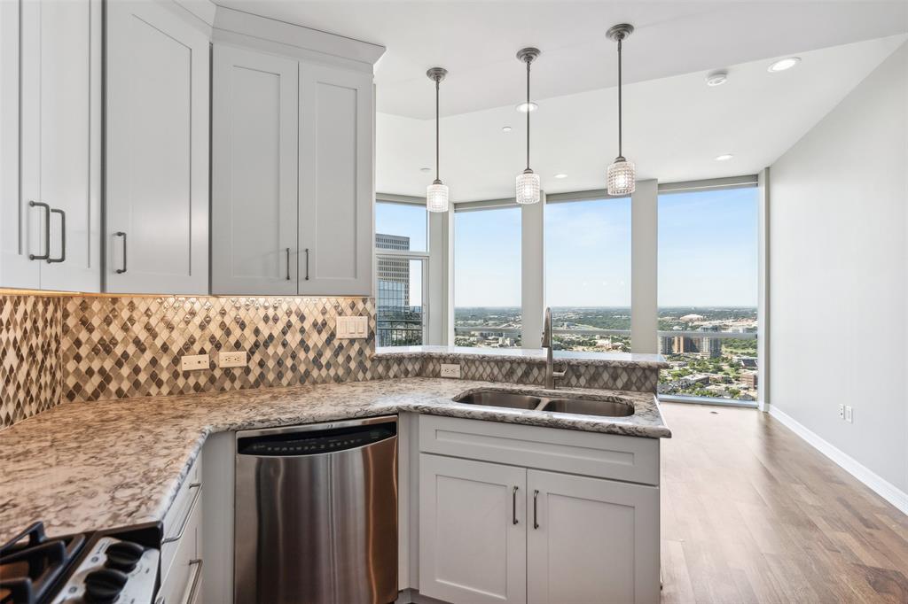 a kitchen with stainless steel appliances granite countertop a sink a stove and a wooden floor