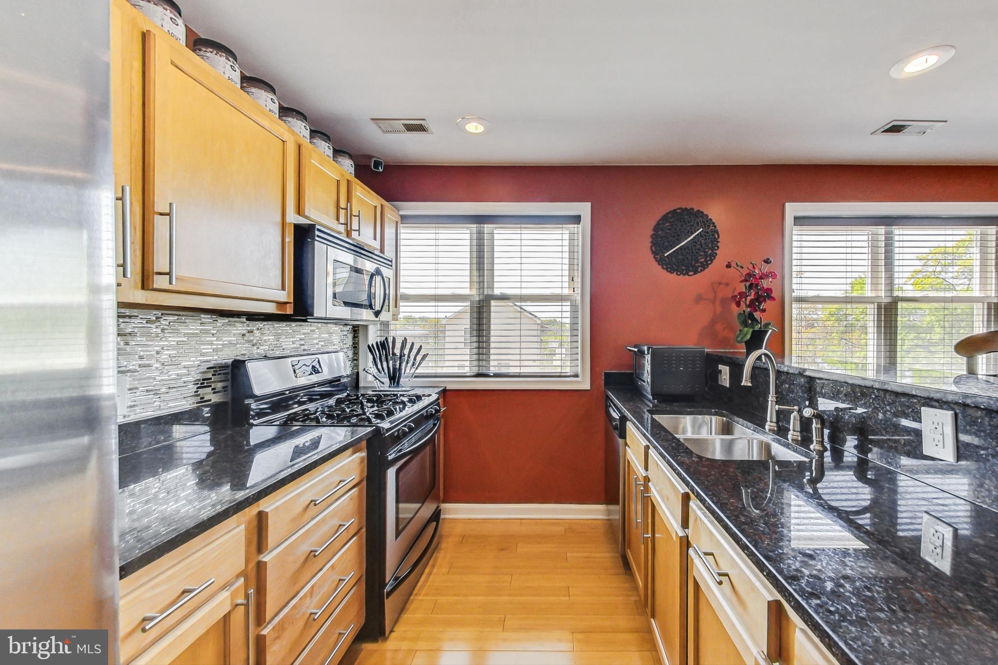 a kitchen with stainless steel appliances granite countertop a stove a sink and a microwave