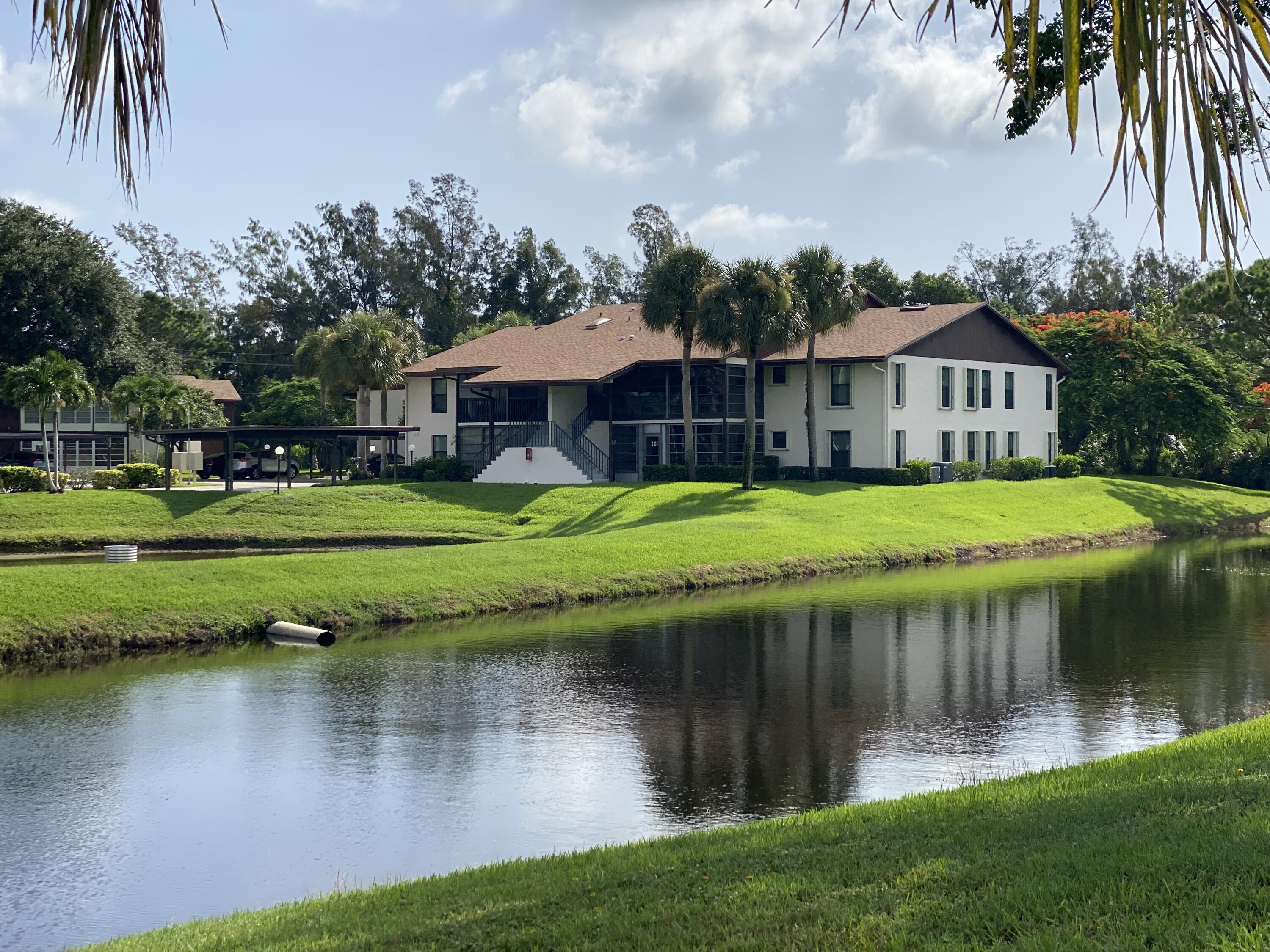 a view of a house with a big yard and palm trees