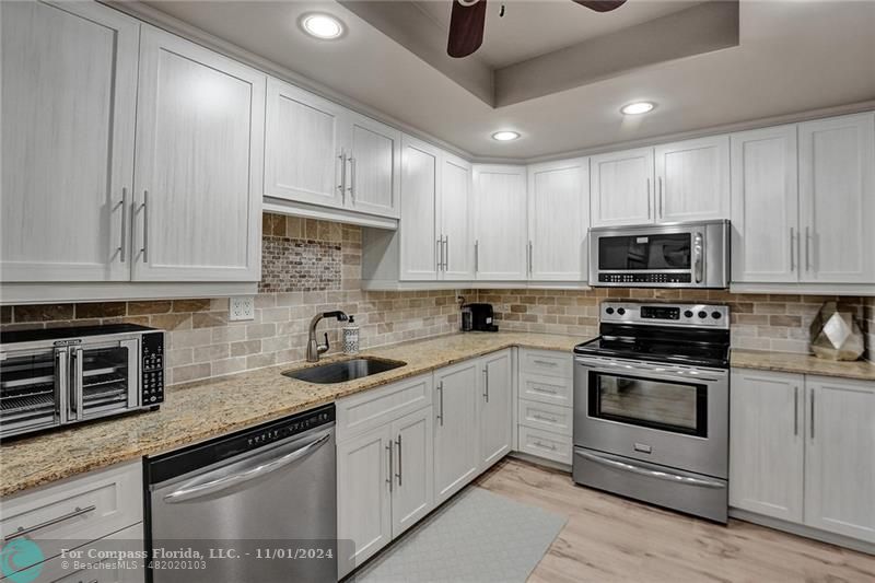 a kitchen with granite countertop white cabinets stainless steel appliances and a sink