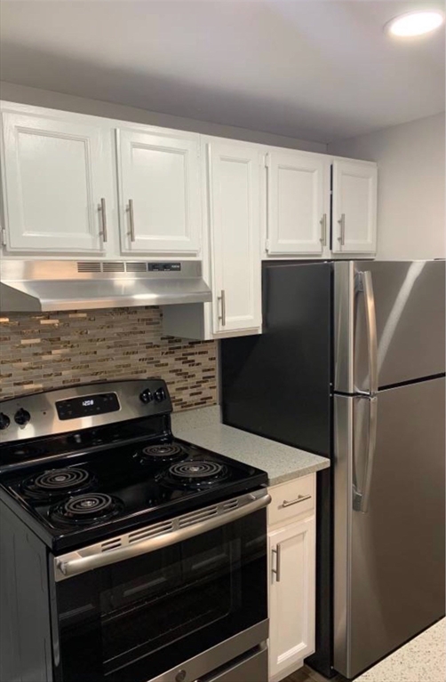 a kitchen with granite countertop white cabinets and refrigerator