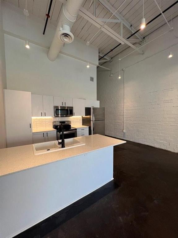 a large room with kitchen island stainless steel appliances