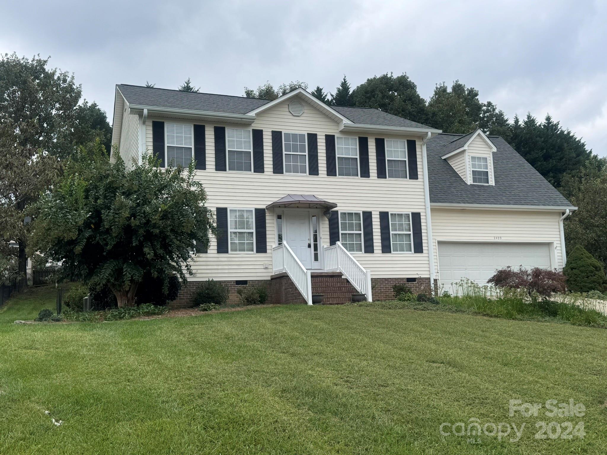 a front view of a house with a yard and trees