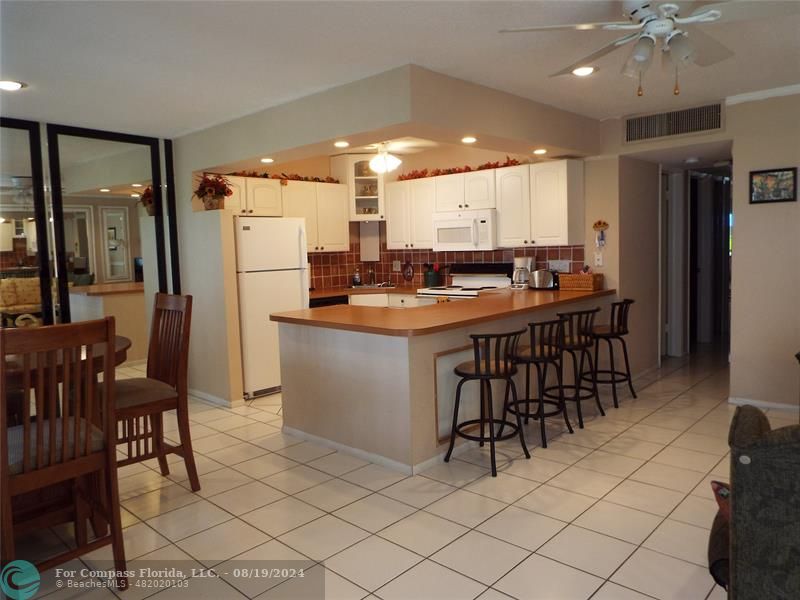 a kitchen with stainless steel appliances kitchen island granite countertop a table chairs sink and cabinets