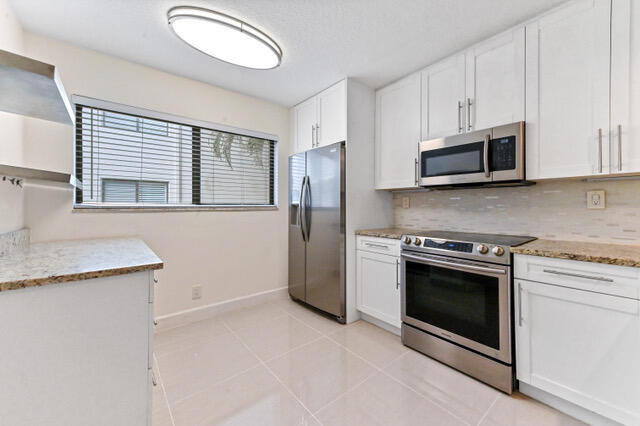 a kitchen with granite countertop wooden cabinets stainless steel appliances and a sink