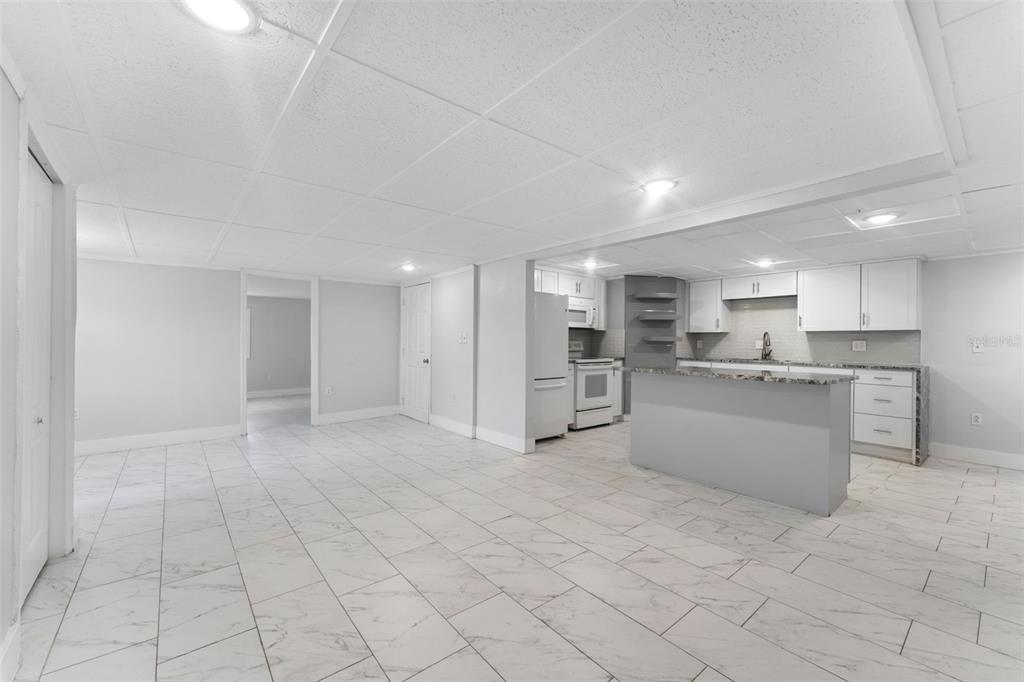 a large white kitchen with a refrigerator a sink and white cabinets