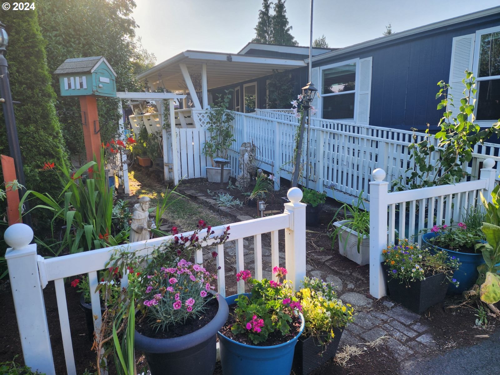 a view of a house with wooden fence and potted plants