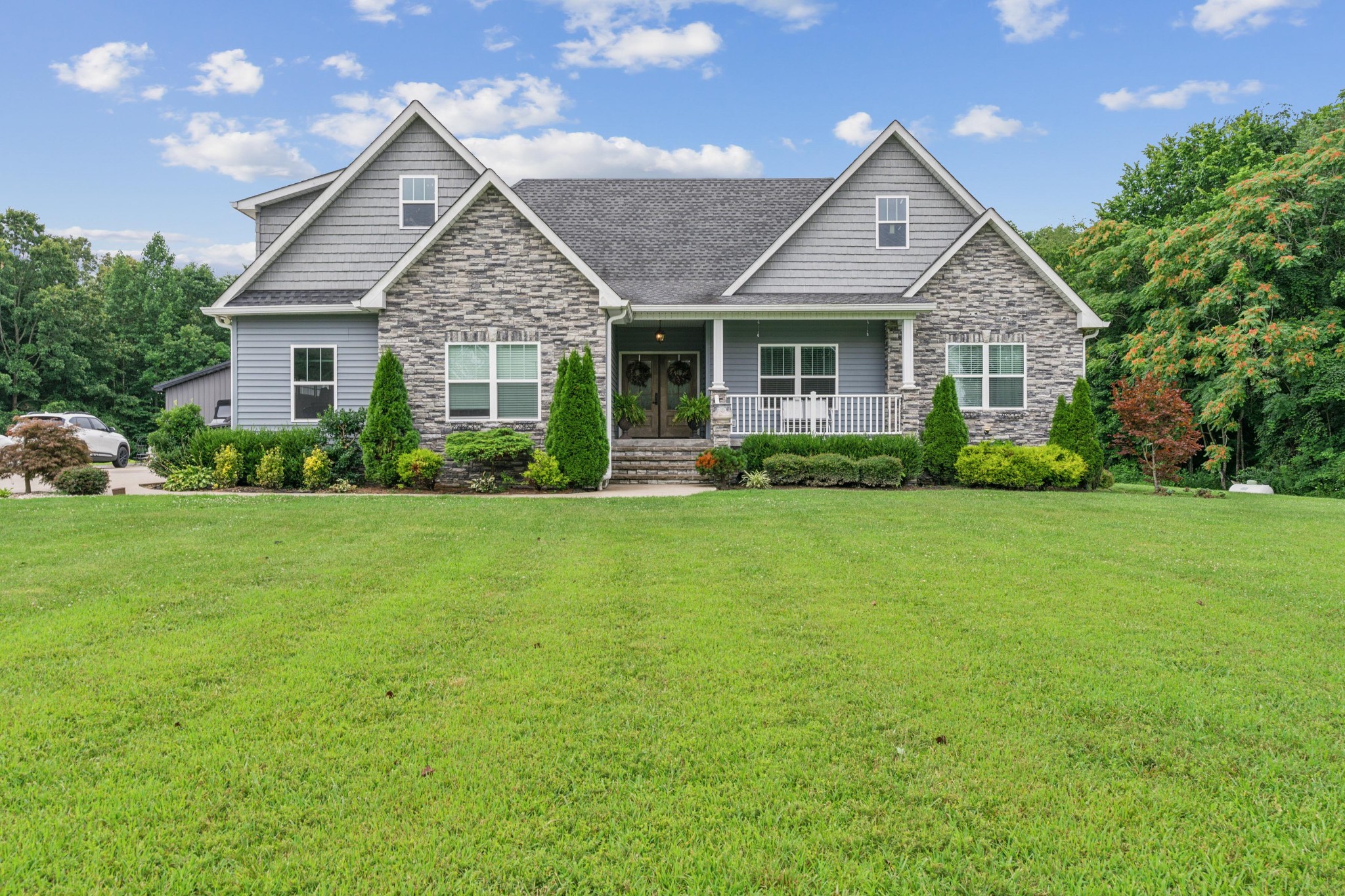 a front view of a house with a yard and green space