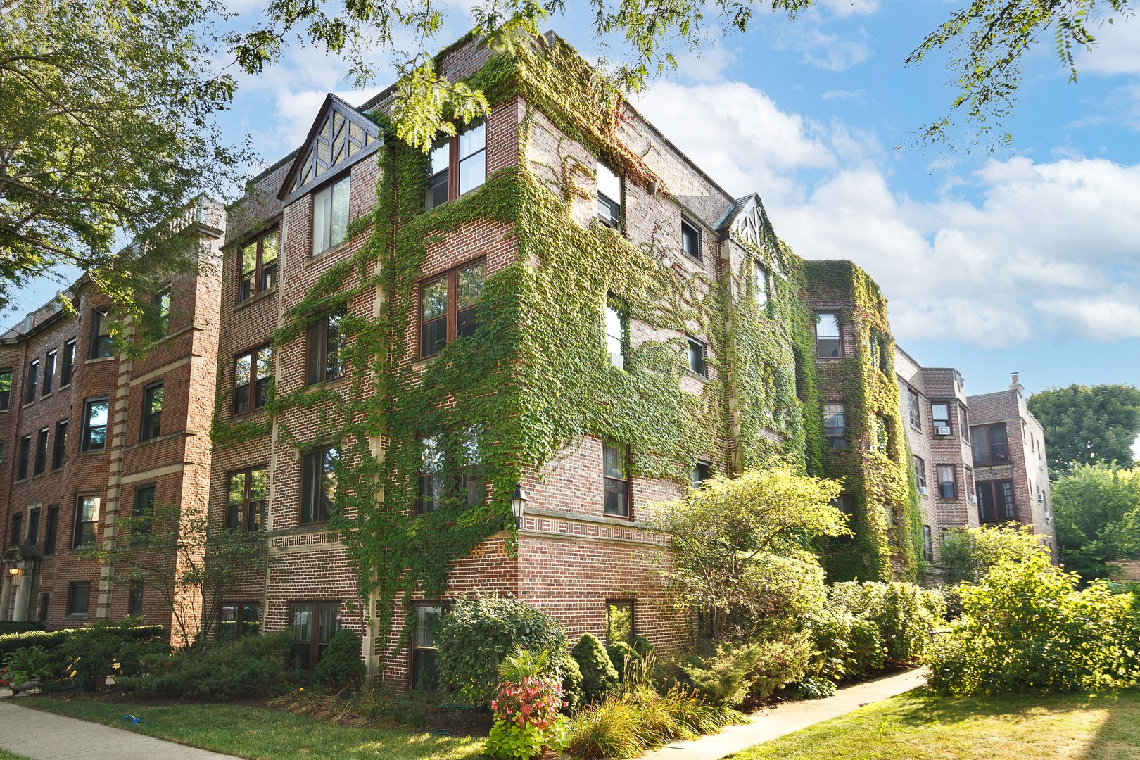 a front view of a multi story residential apartment building with yard and parking space