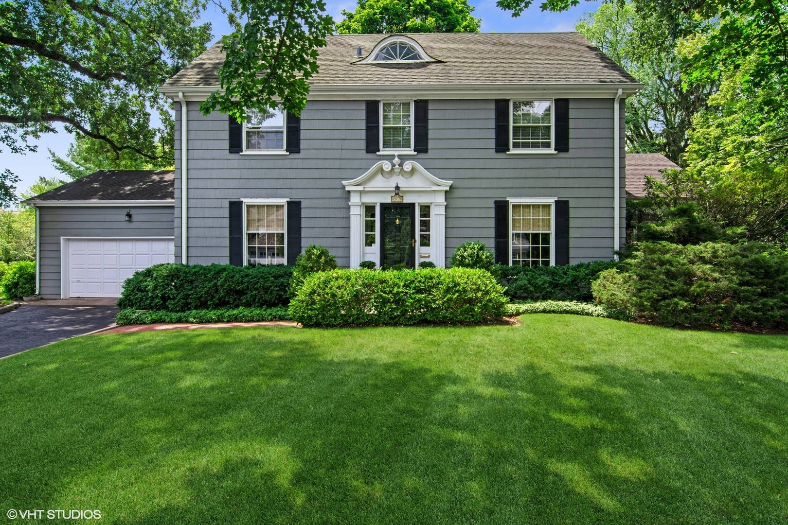 a front view of a house with a yard and trees