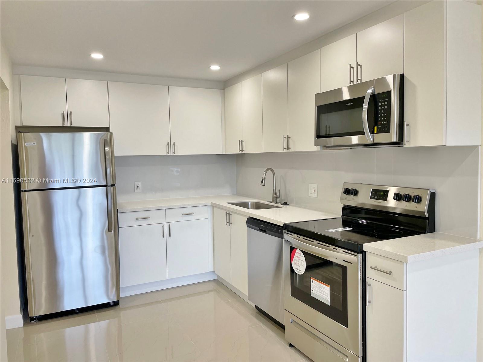 a kitchen with stainless steel appliances granite countertop white cabinets a stove a microwave and a refrigerator