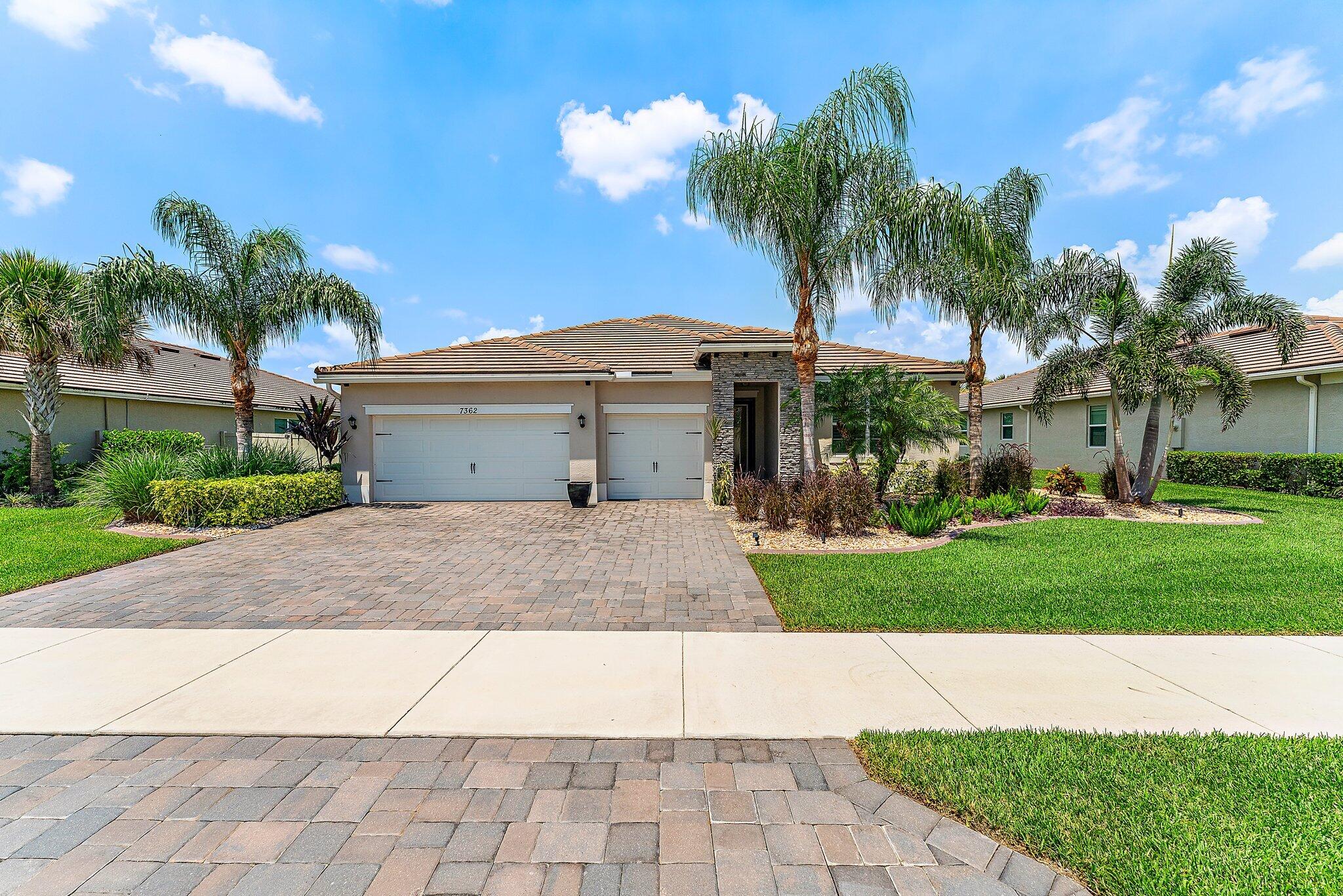 a front view of a house with a garden and palm trees