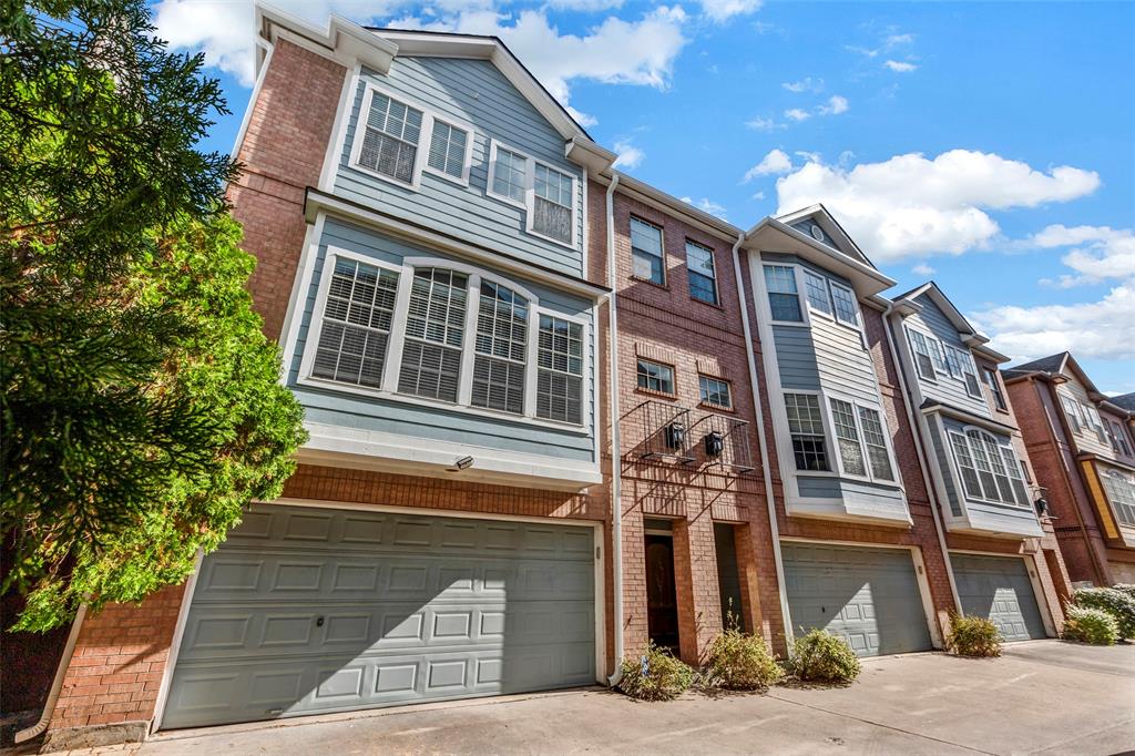 This is a modern 3 story townhome with a brick facade, featuring a garage and large windows, situated in a row of similar homes under a clear blue sky and in the best location! In the heart of Midtown.