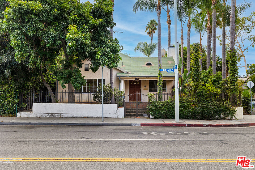 a view of a house with a yard and palm trees