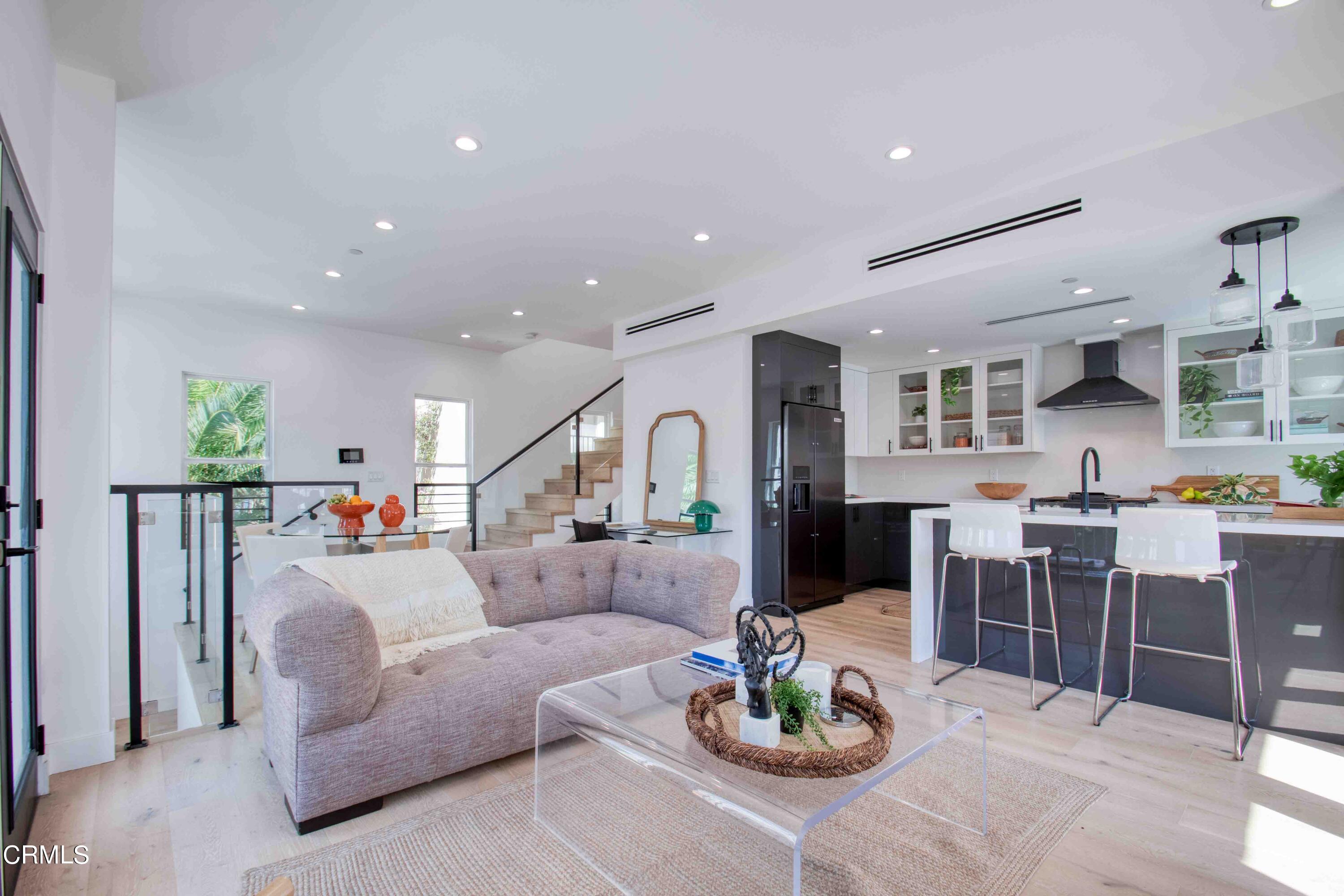 a living room with furniture kitchen view and a wooden floor