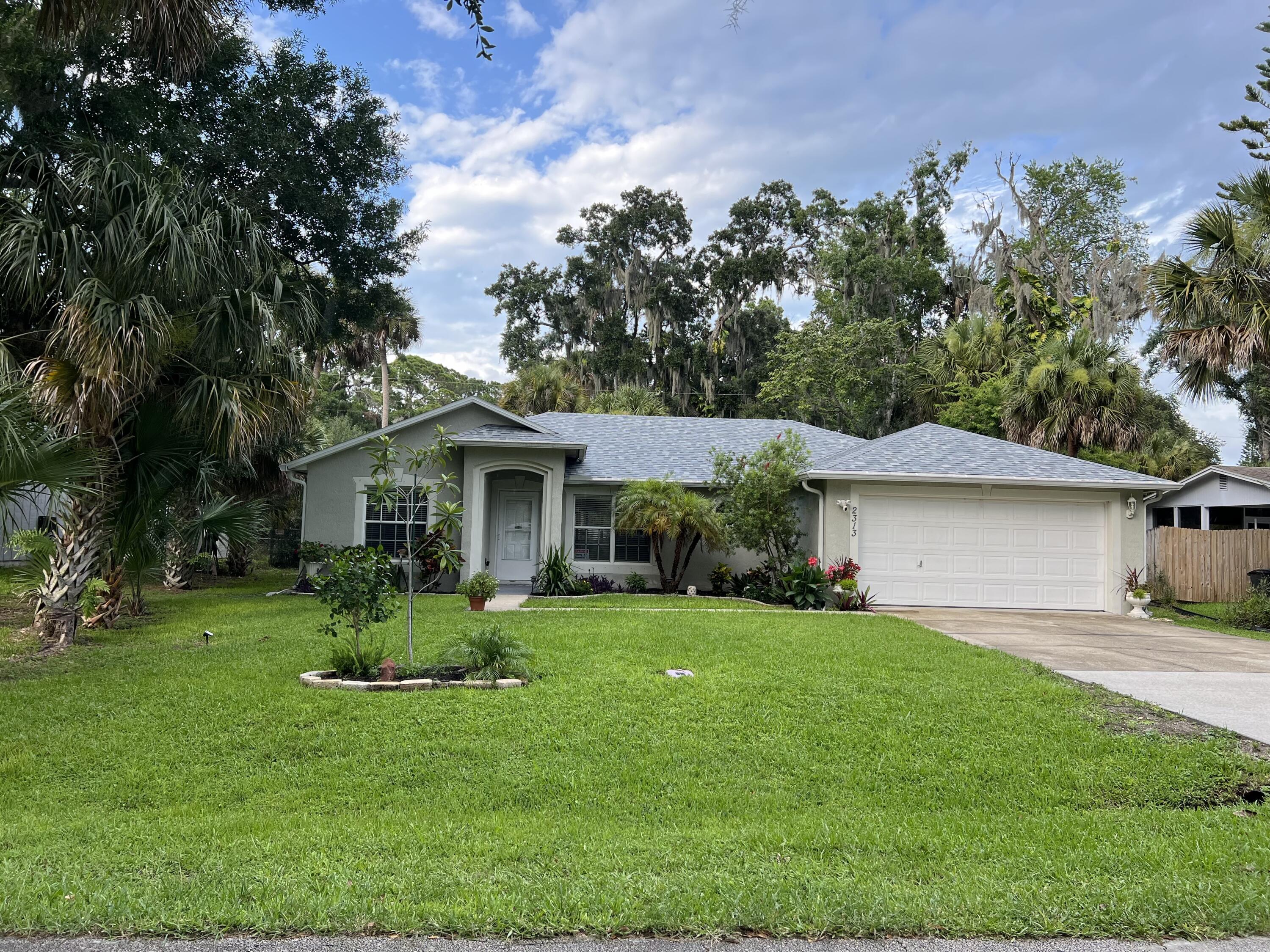 a front view of a house with a yard and tree