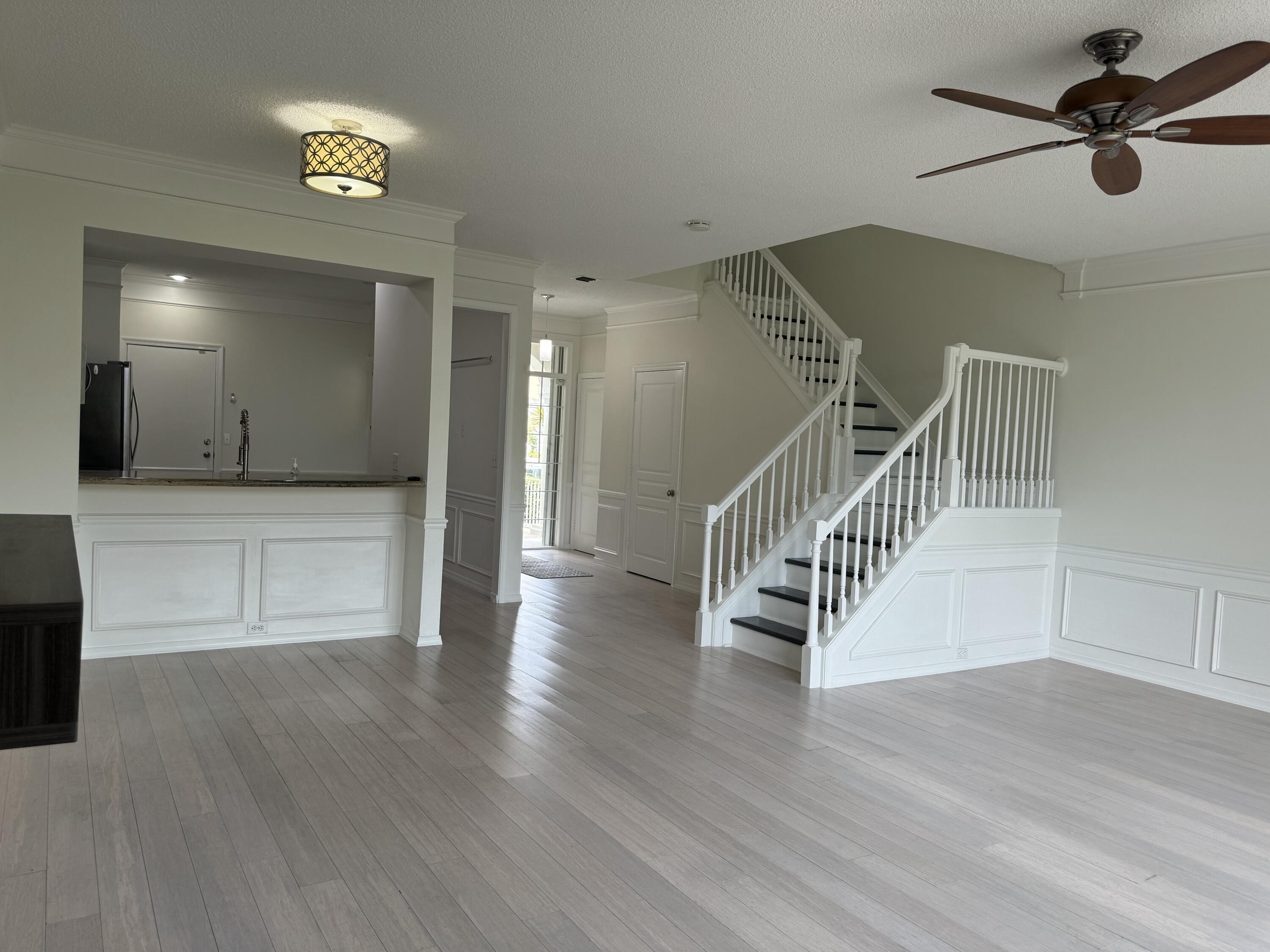 a view of an empty room with wooden floor and a ceiling fan