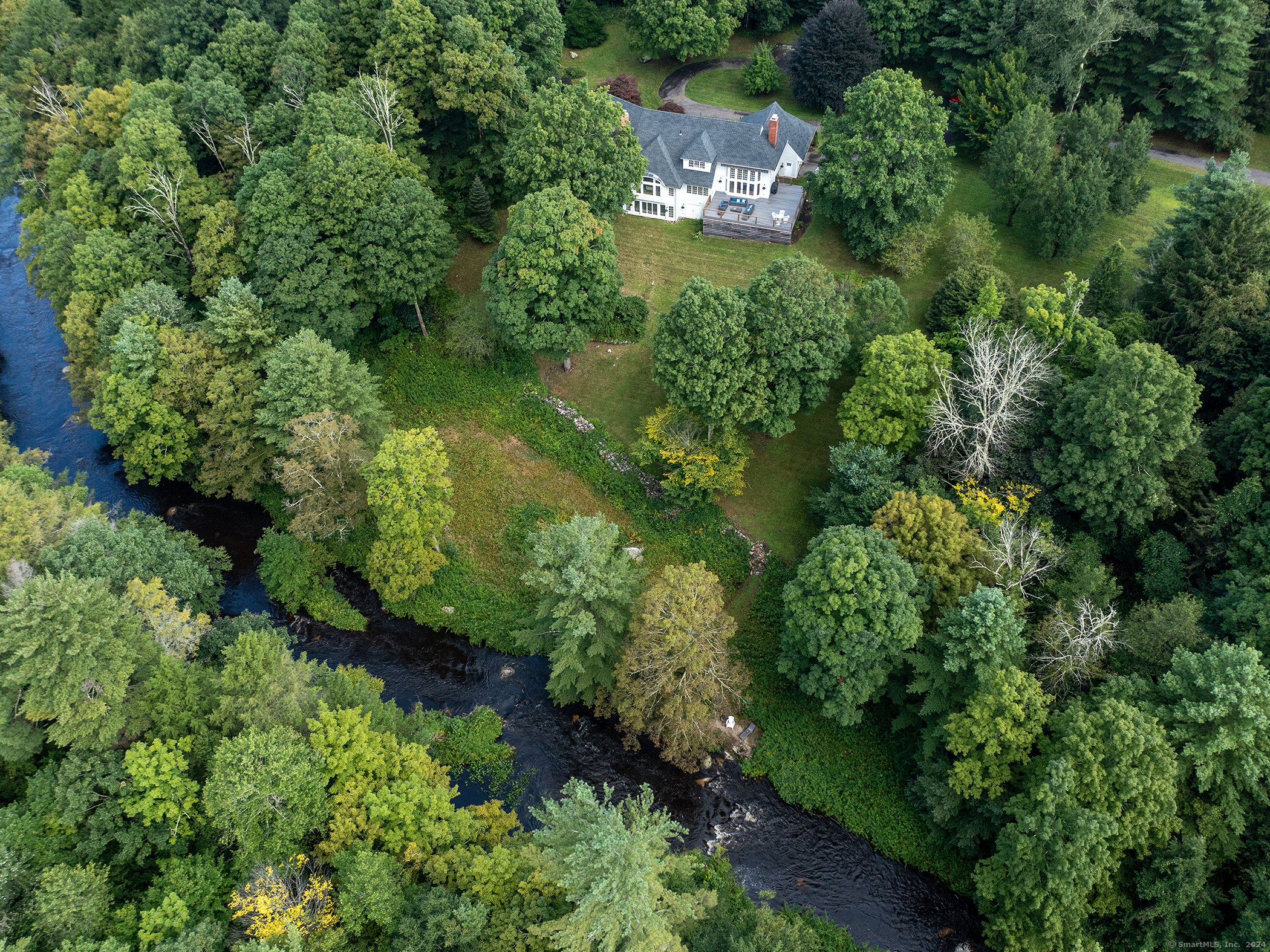 an aerial view of residential house with outdoor space and trees all around