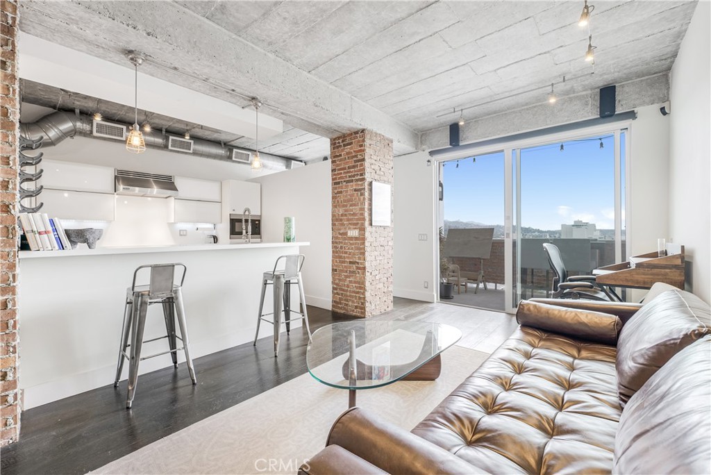 a living room with furniture kitchen view and a large window