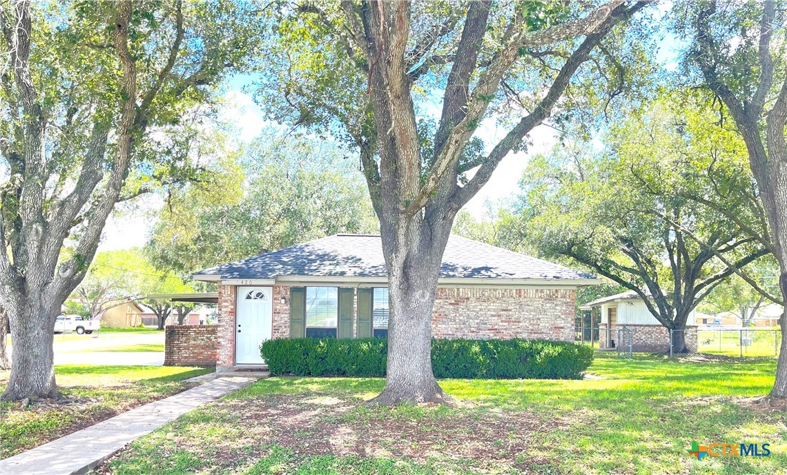 a front view of a house with garden and trees