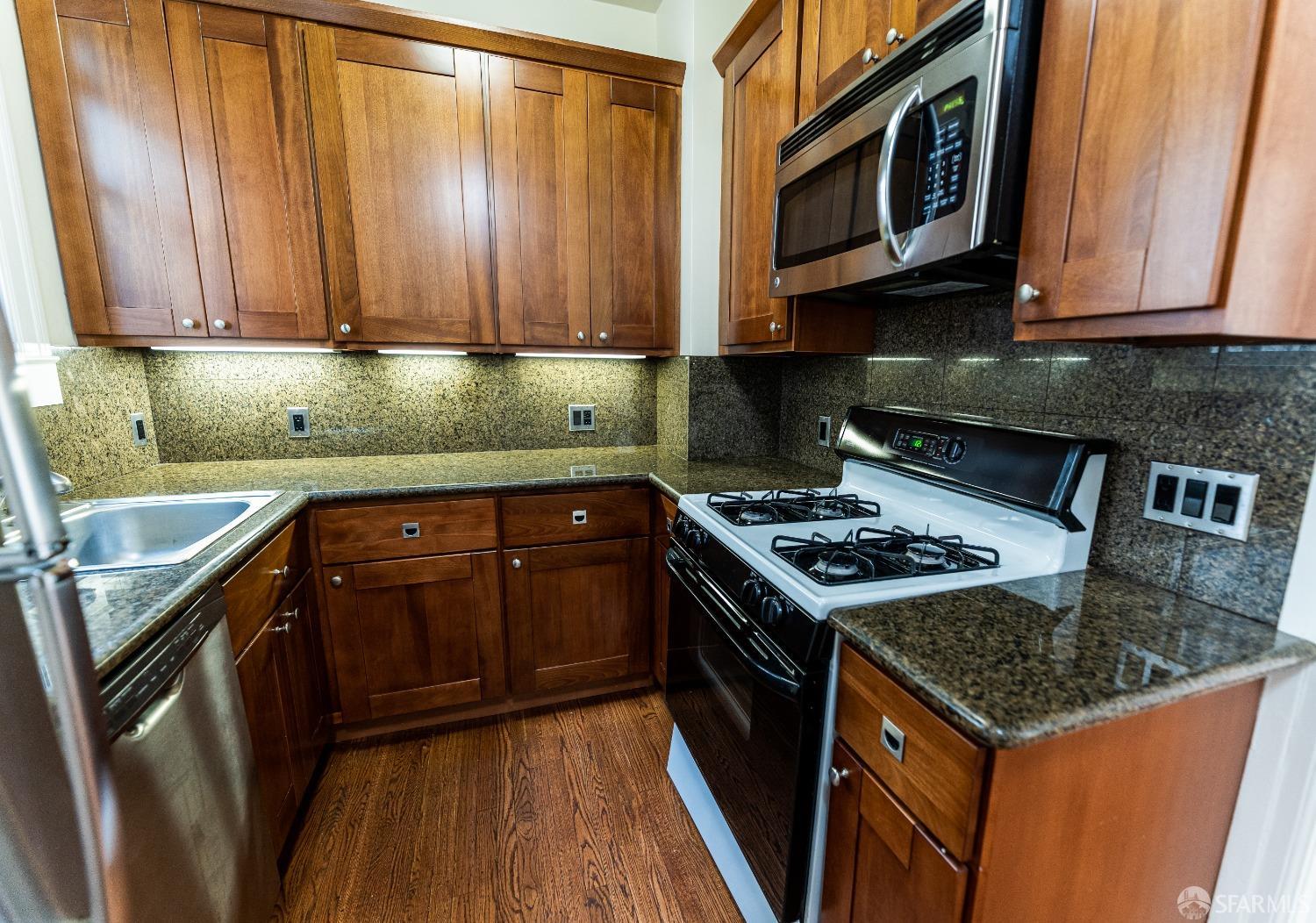 a kitchen with granite countertop a stove top oven microwave and cabinets