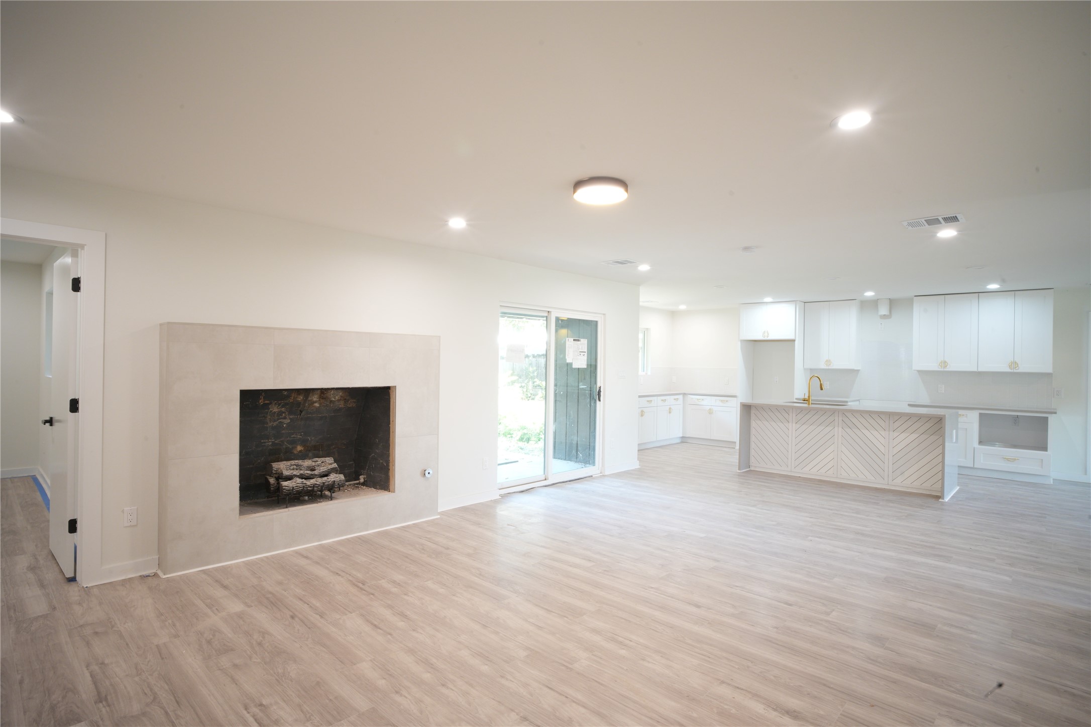 a view of empty room with kitchen and fireplace