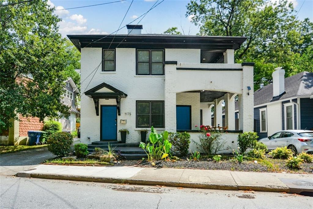 a front view of a house with a yard and potted plants