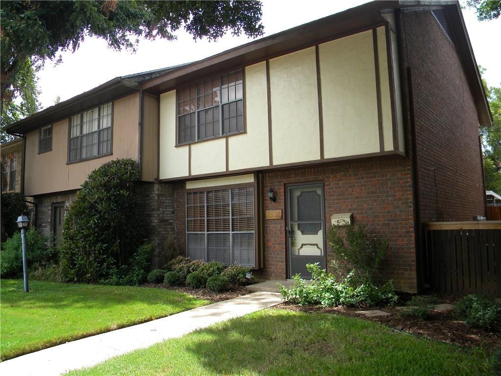 a view of a house with brick walls and a yard with plants