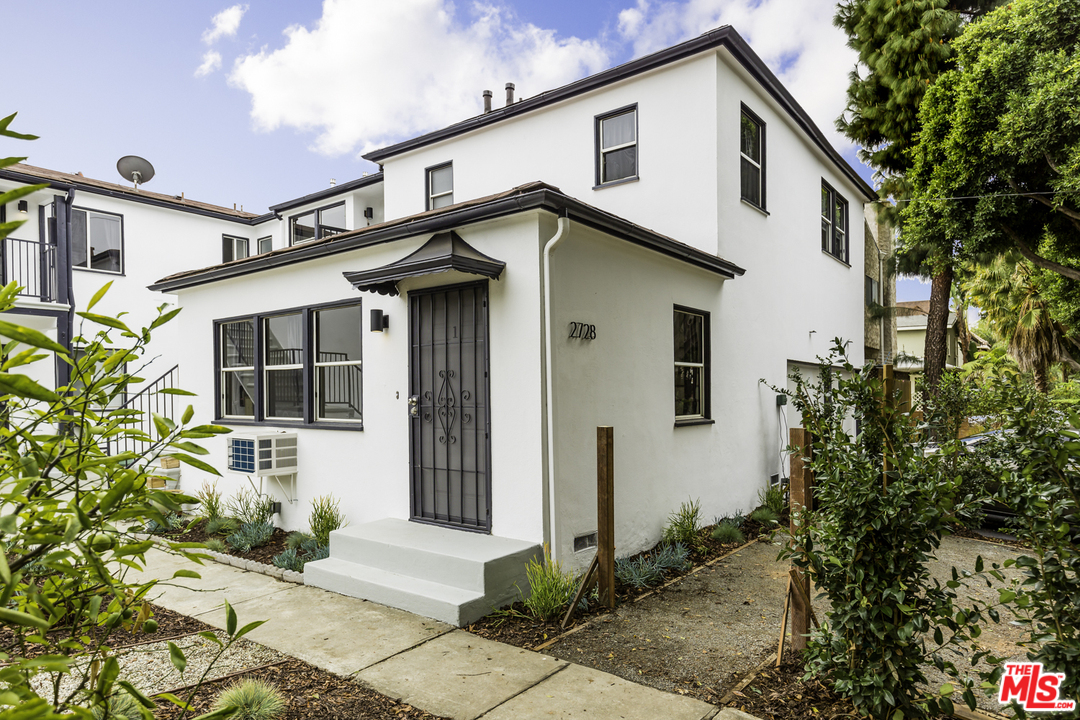 a front view of a house with a yard and potted plants