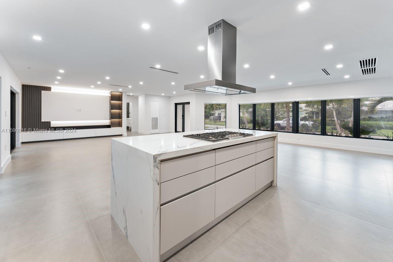 a large white kitchen with a large counter top and stainless steel appliances